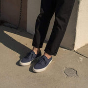 Men's Legend Sneaker in True Navy canvas, worn with dark cropped pants on pavement