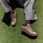 Men's Ridge Urban Hiker hiking sneaker in Desert Palm suede, worn with gray pants and dark socks on green grass