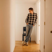 Men's Acorn Trainer sneaker in Tan suede, worn with jeans by a person leaning in a doorway