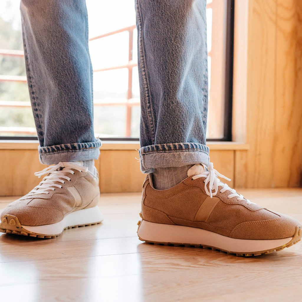 Men's Acorn Trainer sneaker in Tan suede, full-length close-up worn with jeans in front of a window