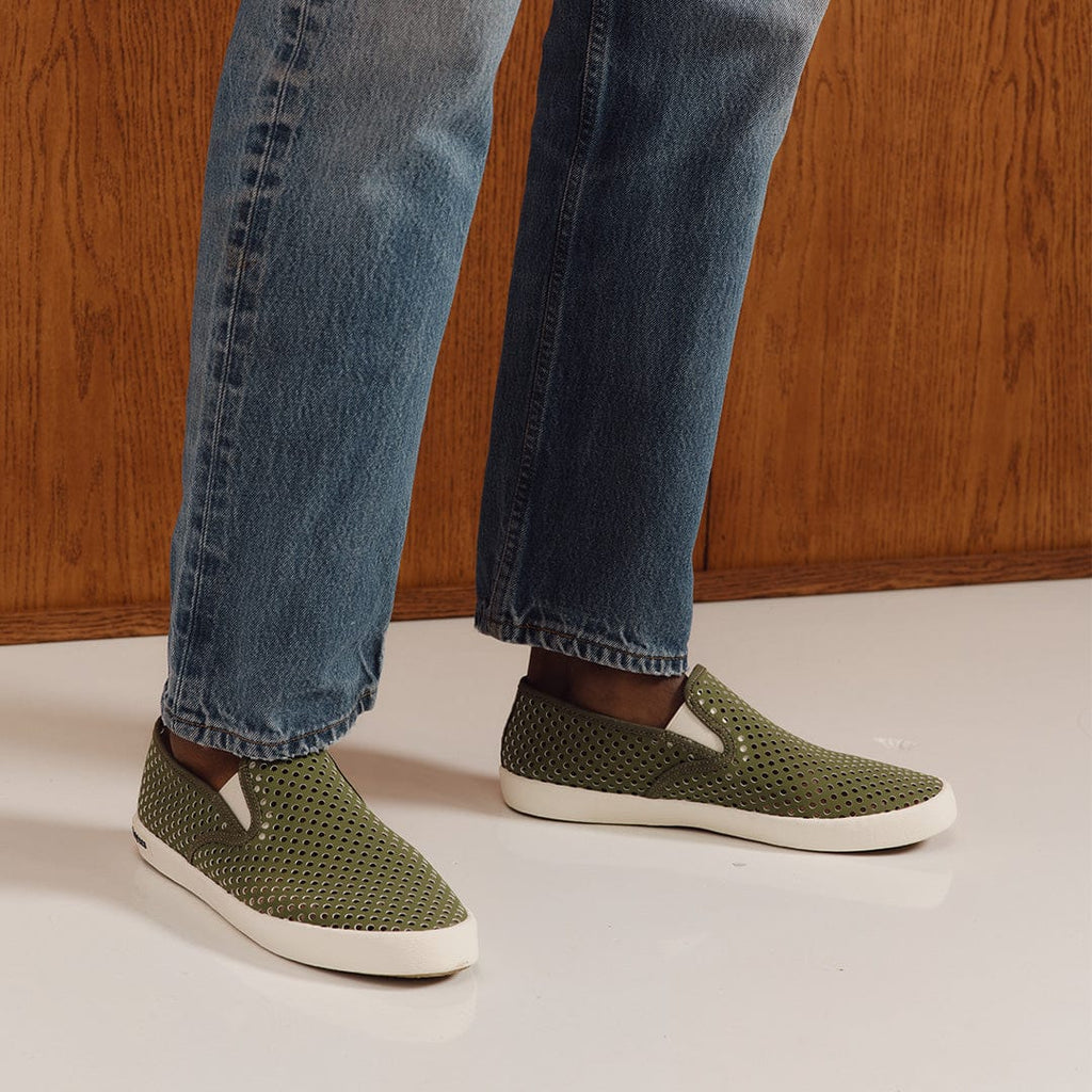 Men's Baja Slip On in Surplus Green vegan nubuck, worn with light jeans on a white floor