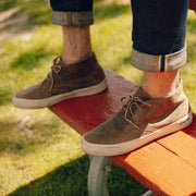 Men's Maslon Desert Boot in Elmwood leather, close-up worn with cuffed jeans on a red bench
