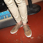 Men's Hermosa Sneaker in Elmwood leather, close-up worn with khaki pants on a red floor