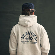 Person in an oatmeal SeaVees x Camber hoodie, back view with graphic