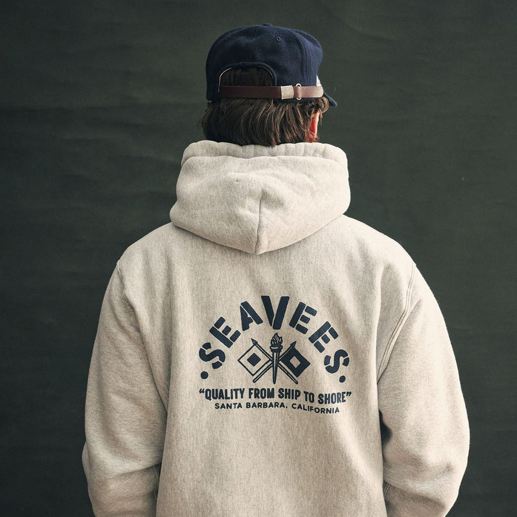 Person in an oatmeal SeaVees x Camber hoodie, back view with graphic