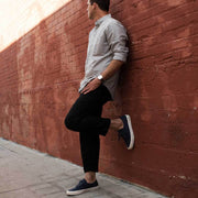 Men's Legend Sneaker in True Navy canvas, worn by a person leaning against a red brick wall
