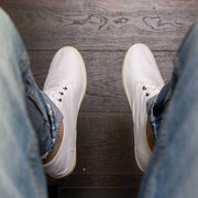 Men's Sixty Six Sneaker in White canvas, viewed from above, worn with jeans on a wood floor