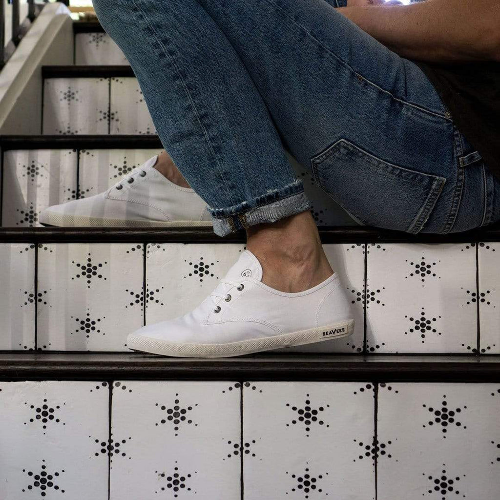 Men's Sixty Six Sneaker in White canvas, worn with jeans on patterned tile stairs