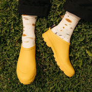 Men's Bodega Clog in Calendula rubber, close-up worn with patterned socks on grass