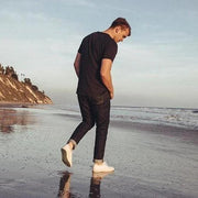 Men's Legend Sneaker in Bleach canvas, worn by a person walking on a beach at low tide