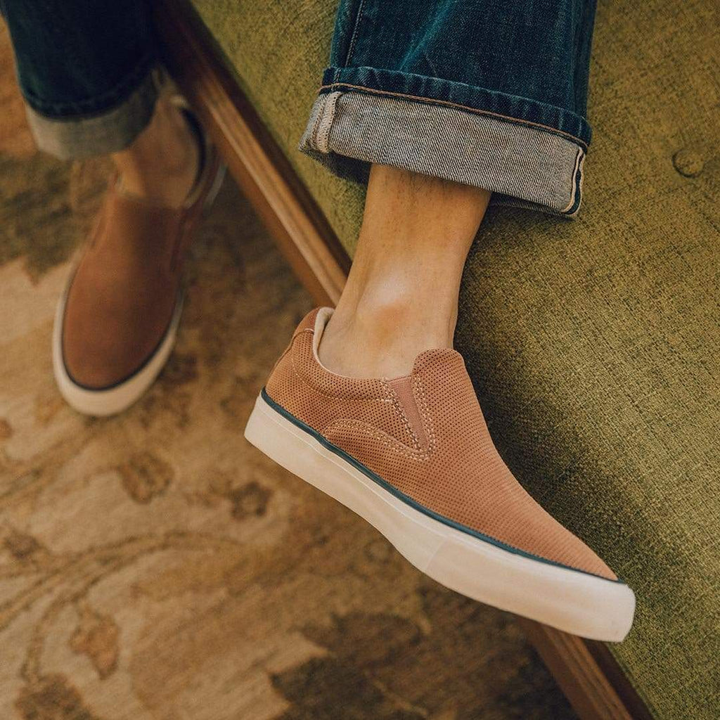Men's Hawthorne Slip On in Terracotta suede, close-up worn with cuffed jeans on a green sofa