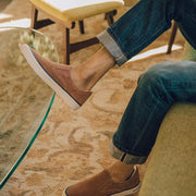Men's Hawthorne Slip On in Terracotta suede, worn with cuffed jeans by a person seated on a sofa, overhead angle
