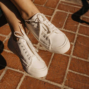 Women's SeaChange LTT sneaker in White Corn Leather, close-up worn on red brick tiles