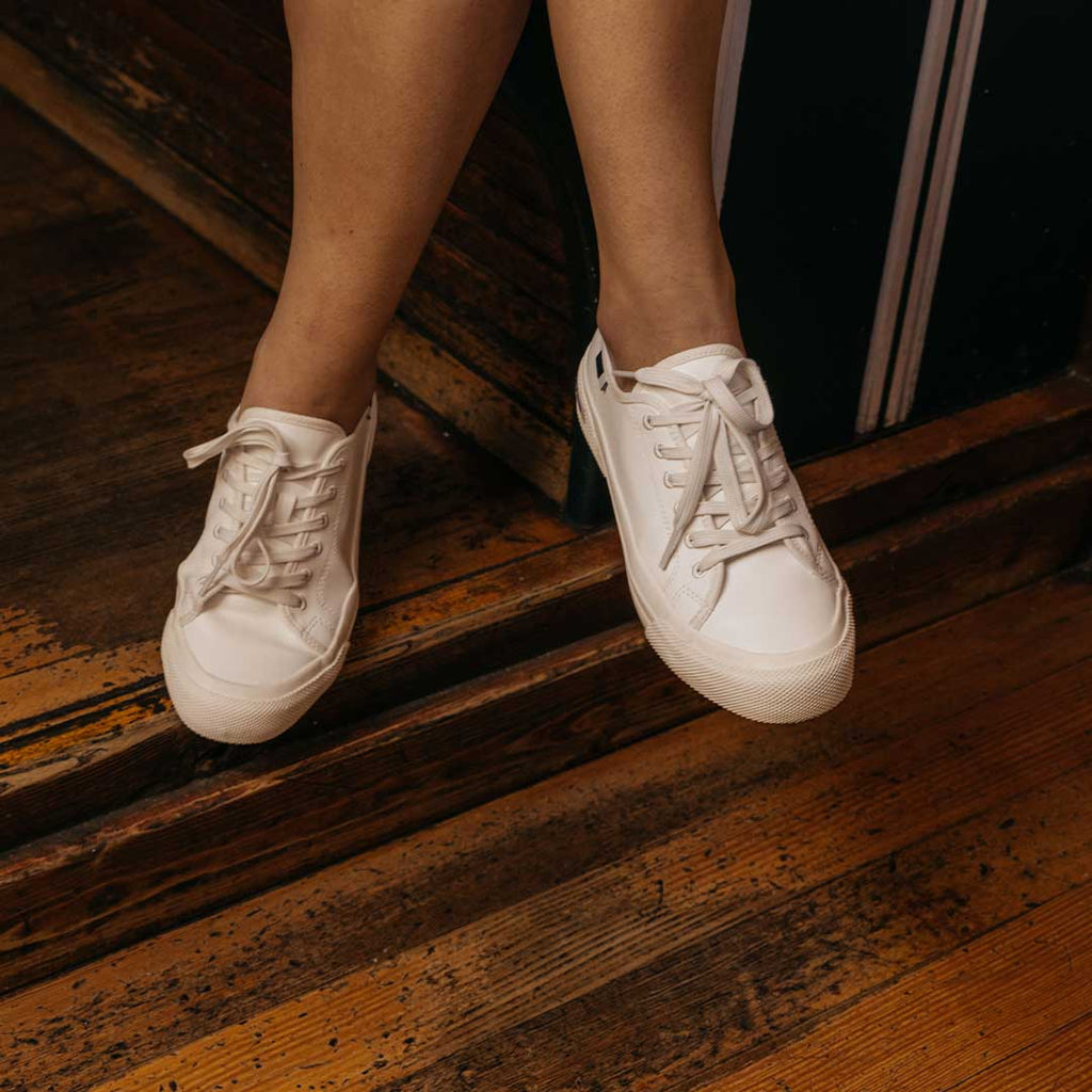 Women's SeaChange LTT sneaker in White Corn Leather, worn with bare ankles on a wood floor
