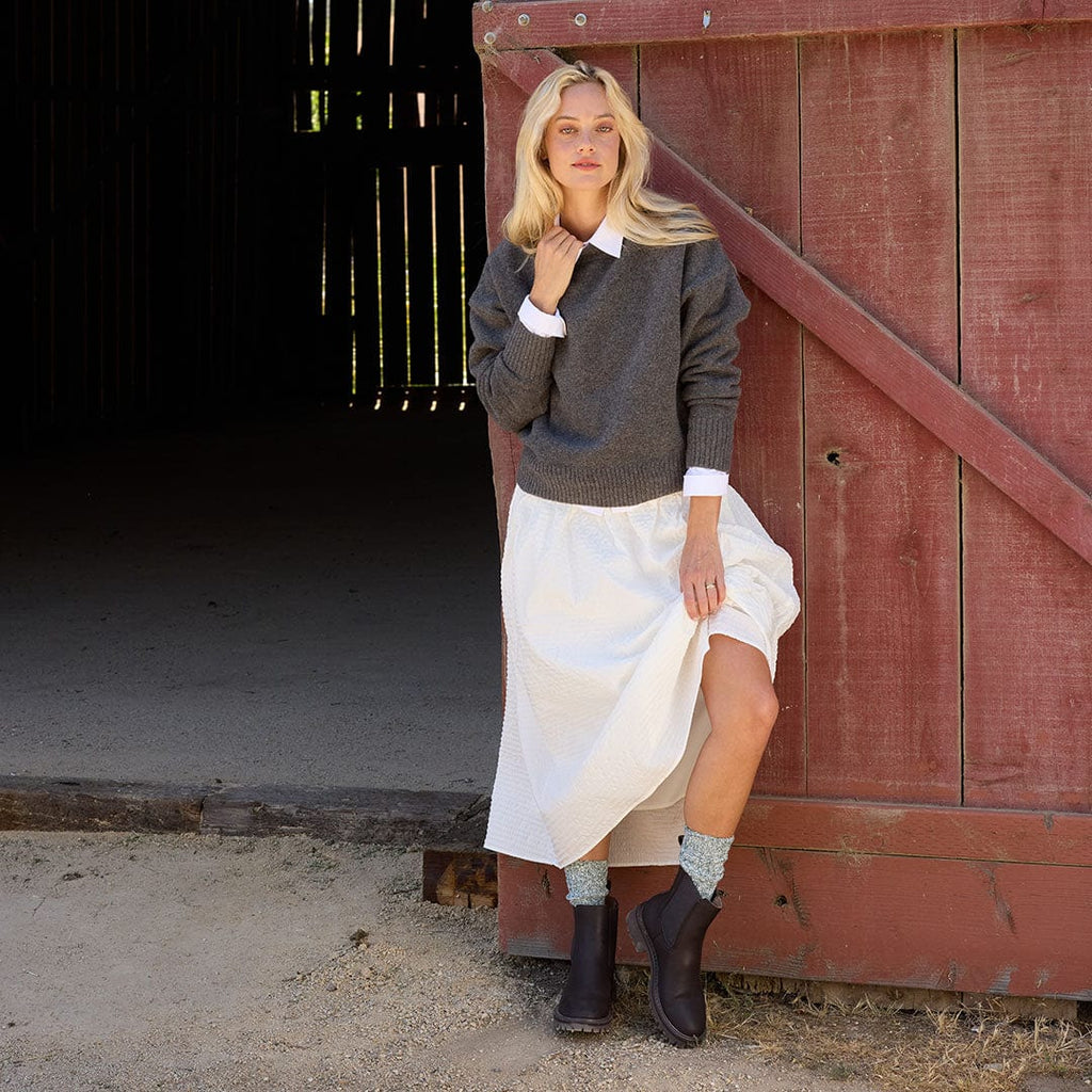 Women's Salt Creek Boot in Dark Chocolate leather, worn by a person standing in front of a red barn door in a white skirt