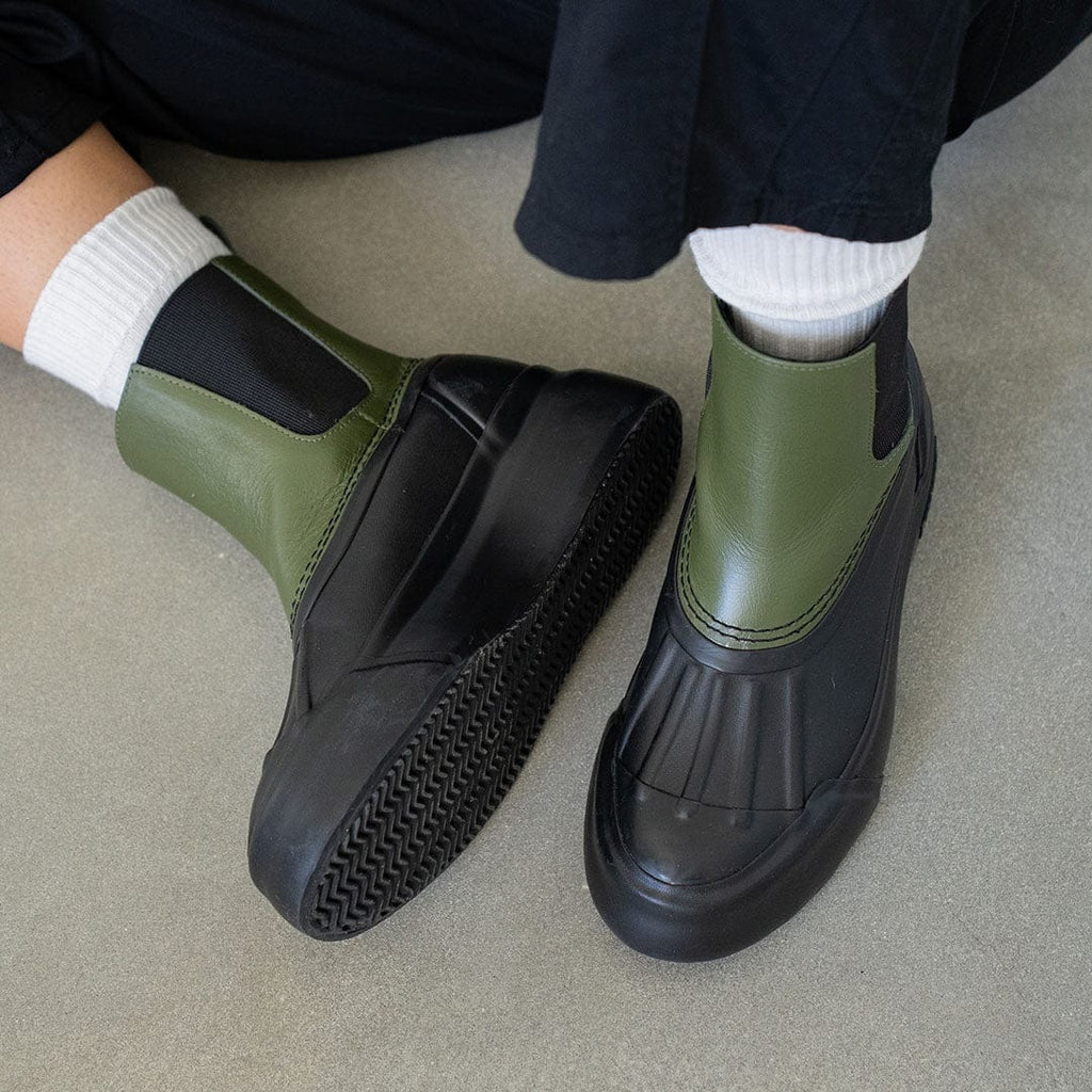 Women's Chalet Chelsea Boot in Utility Olive leather, worn with white socks and black pants, close up