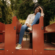 Women's Baja Slip On in Surplus Green canvas, worn with jeans by a person seated on wooden benches