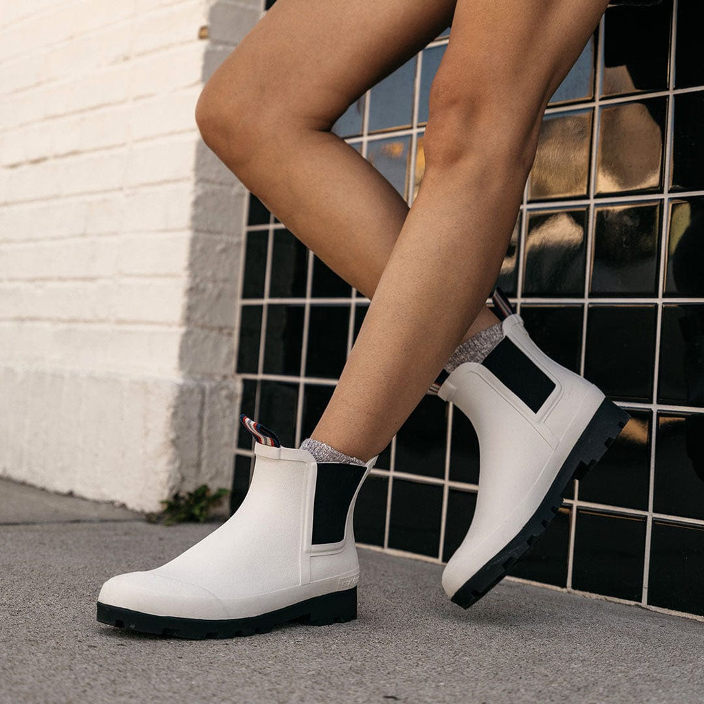 Women's Bolinas Off Shore Boot in Salt rubber, close-up worn with bare legs on a sidewalk